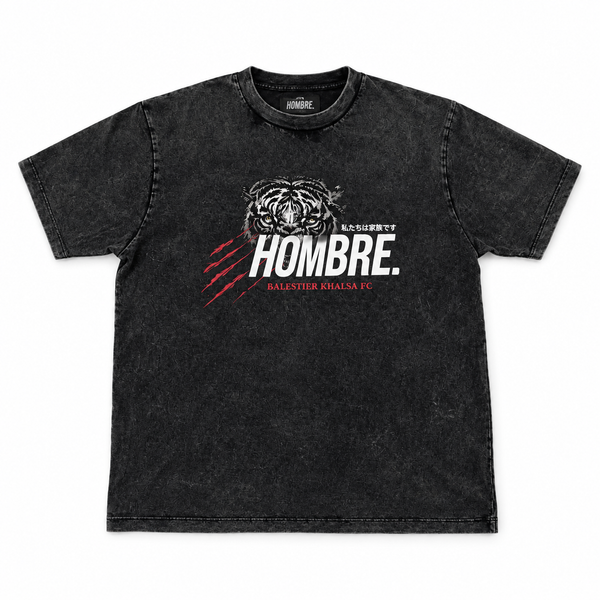 Front of HOMBRE x Balestier Khalsa FC Tiger Instinct washed black tee with tiger graphic, white HOMBRE wordmark and red claw marks