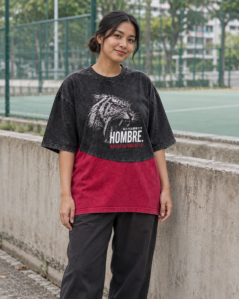 Asian female model wearing the HOMBRE x Balestier Khalsa FC Tiger Fury oversized washed black and red tee beside a sports court