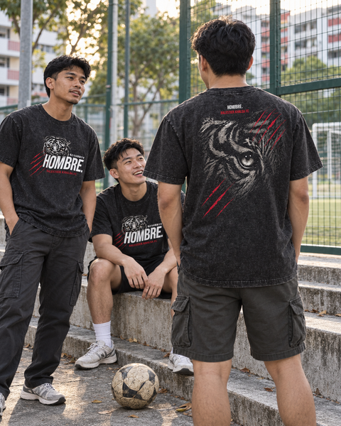 Three Asian men wearing Tiger Instinct regular-fit washed black tees at a football court, showing the front graphic and large tiger-eye back print