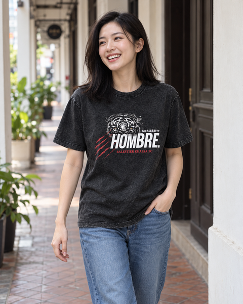 Asian female model wearing the HOMBRE x Balestier Khalsa FC Tiger Instinct regular-fit washed black tee along a Singapore shophouse walkway